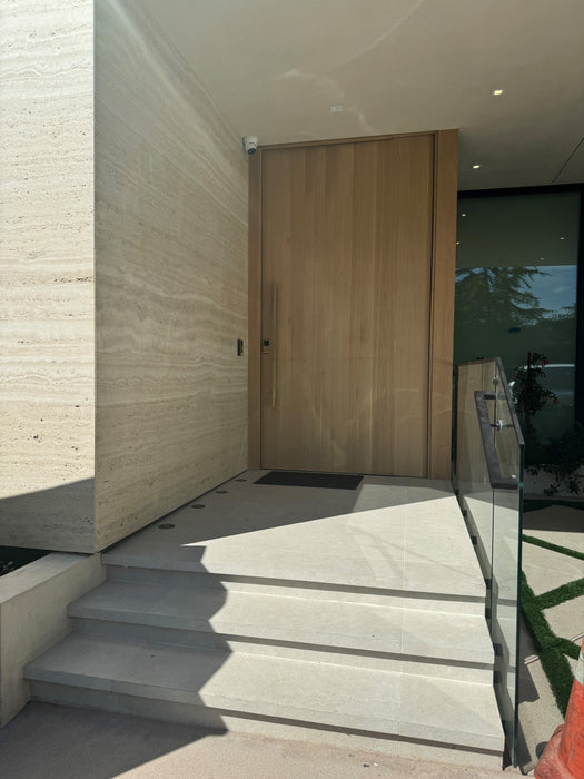 Modern house entrance with a wooden door and concrete steps.
